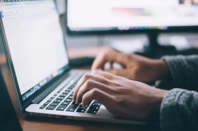 A closeup of someone typing on their laptop.
