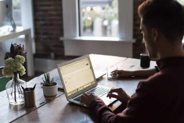 A man using his laptop to work with the best newsletter software for his business.