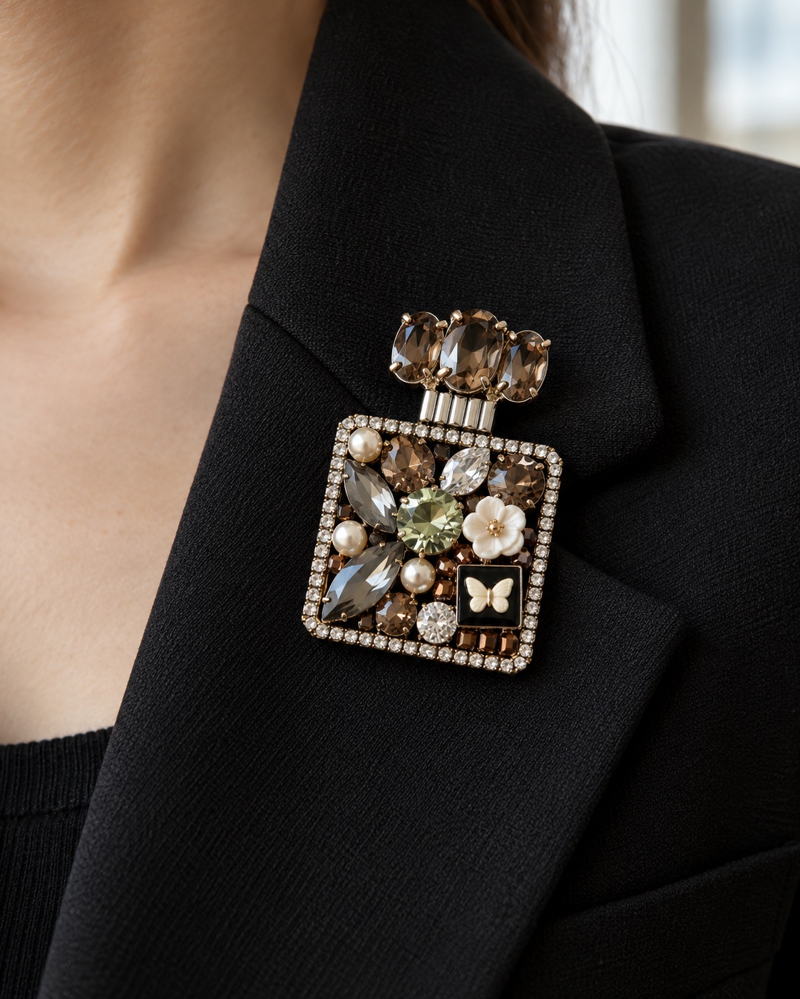 Square jeweled perfume bottle brooch on a black blazer lapel