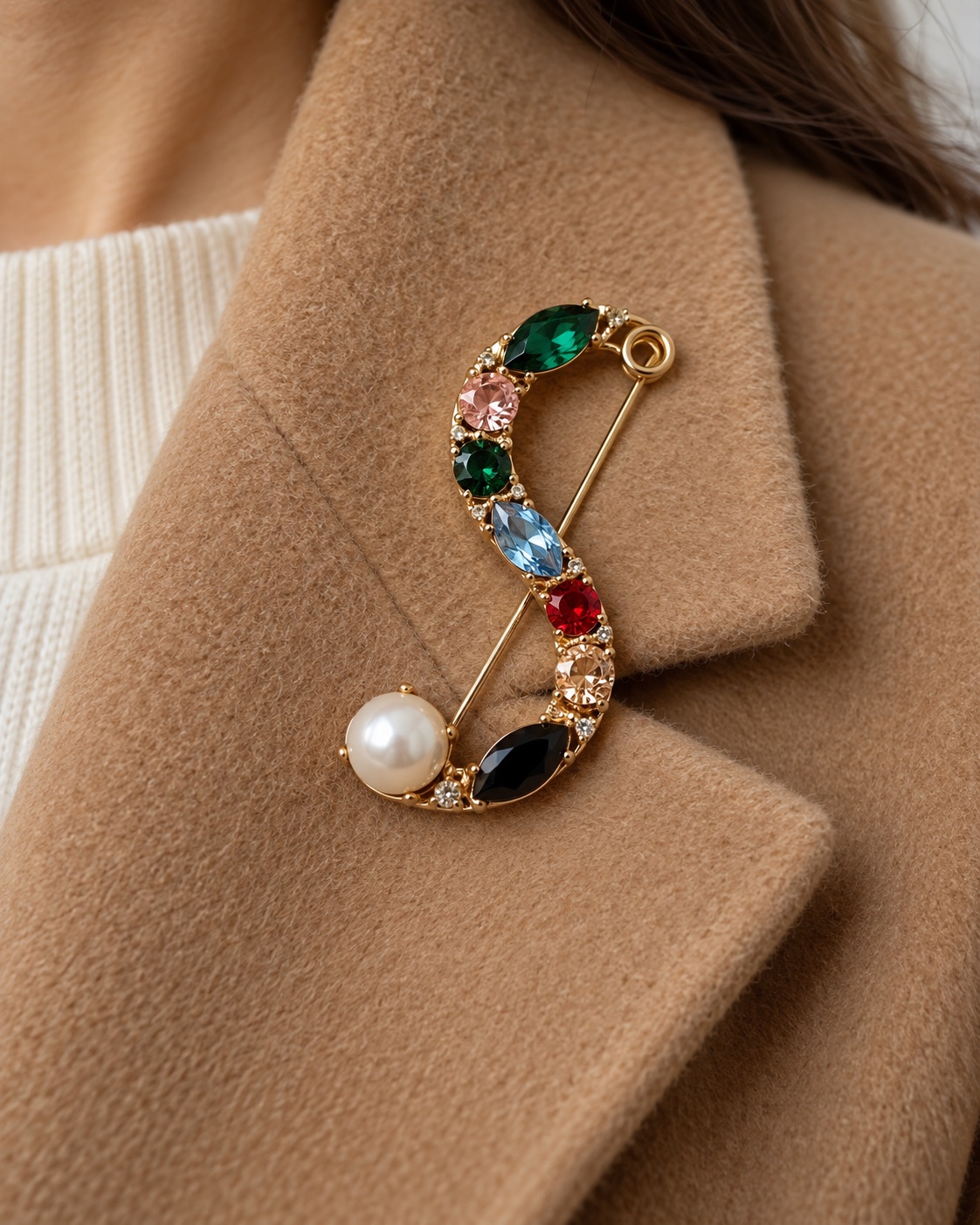 Multicolor S-shaped safety-pin brooch with one pearl on a camel coat