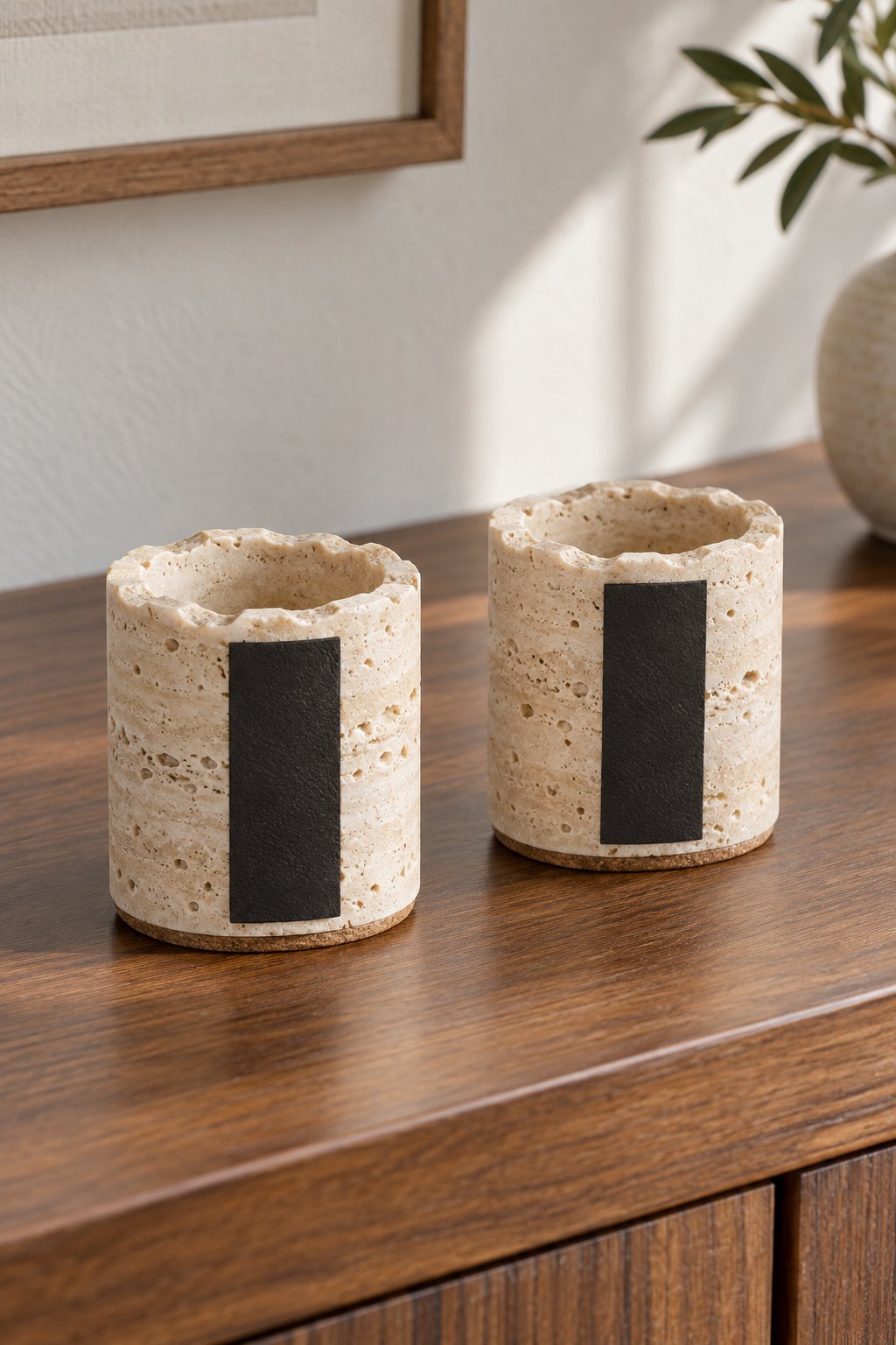 Two porous travertine match holders with black side strikers.